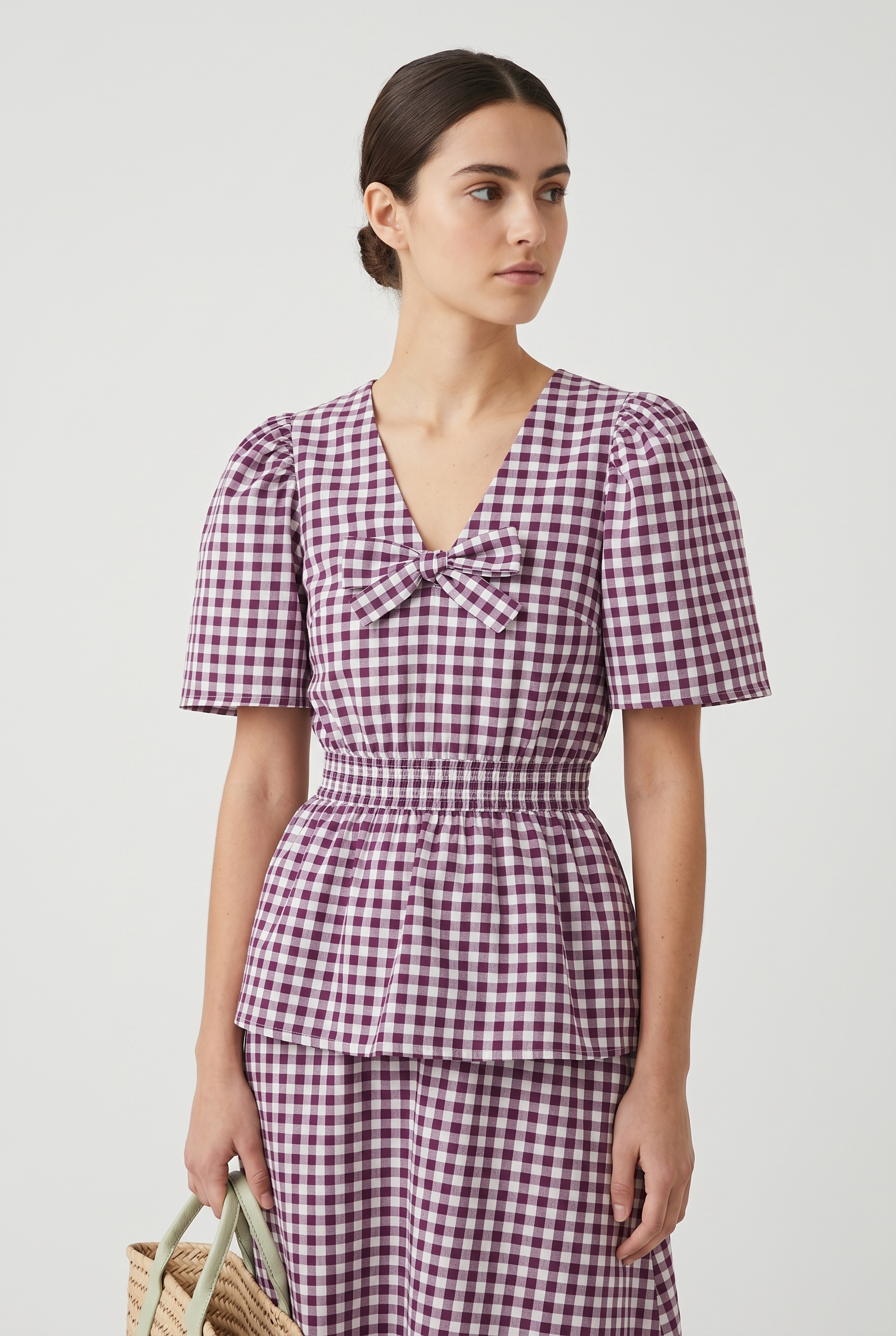 Model wearing aubergine and white gingham puff sleeve V-neck blouse