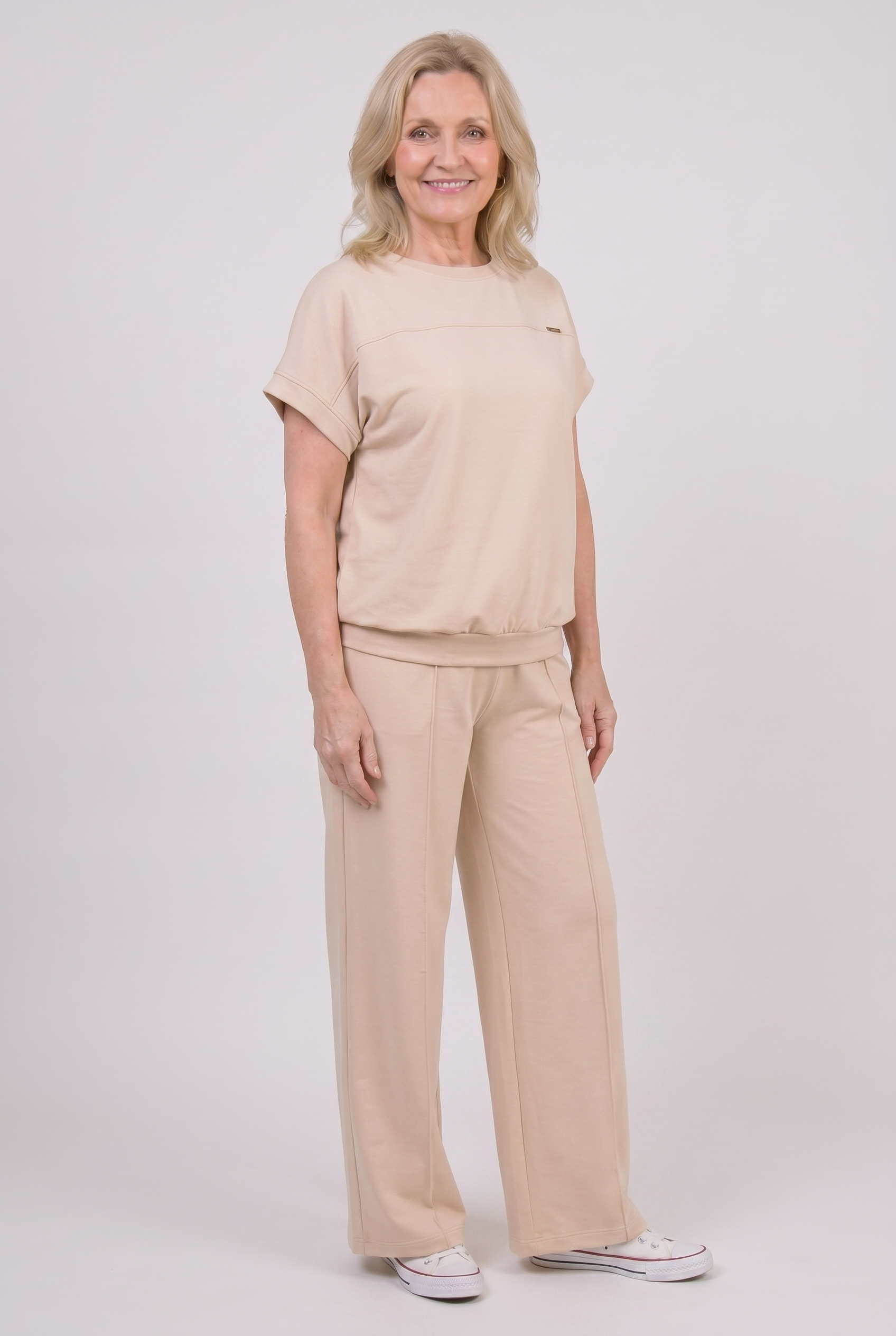Woman wearing beige two-piece loungewear set with wide-leg palazzo trousers