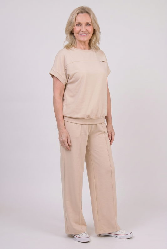 Woman wearing beige two-piece loungewear set with wide-leg palazzo trousers